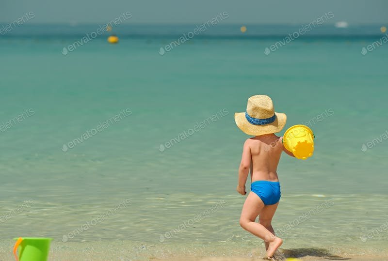 Baby Wearing Yellow Color Bucket Hat Stating On Seaside