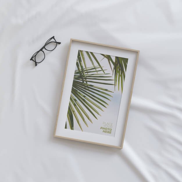 Photo frame mockup with glasses on bed Premium Psd