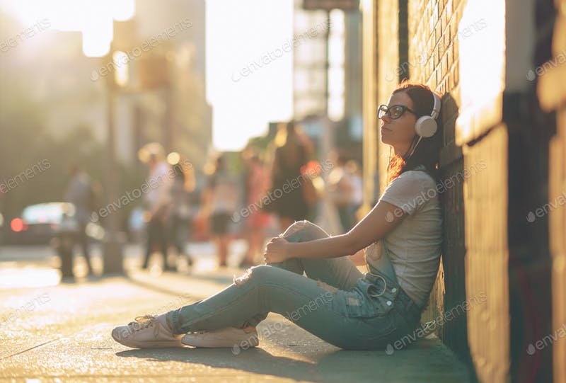 A Girl Sitting In The Street Wearing Earphones PSD Template