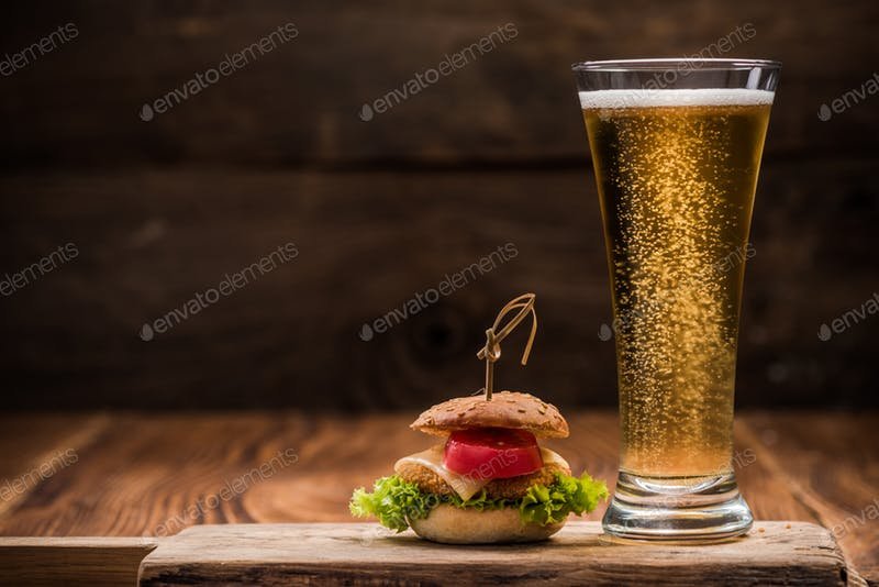 Fresh Beer Glass Placed On Wooden Board With Mini Beef Burger Beside It