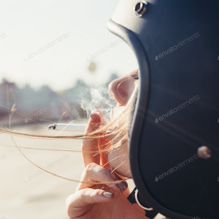 Side View Of A Beautiful Girl Wearing Blue Helmet And Smoking