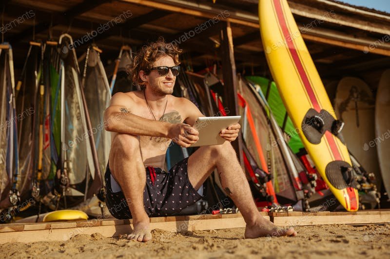 Surfer Man With A PC Tablet In His Hand Mockup.
