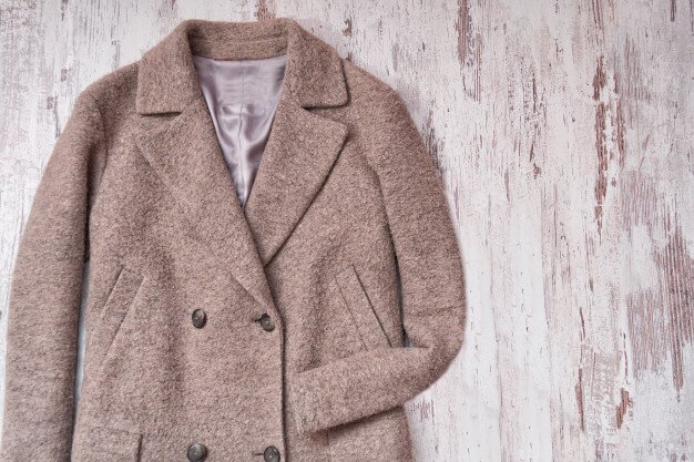 Brown woolen coat, wooden background Premium Photo
