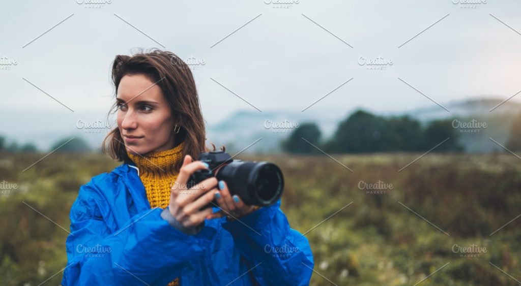 Girl photographer in a blue raincoat