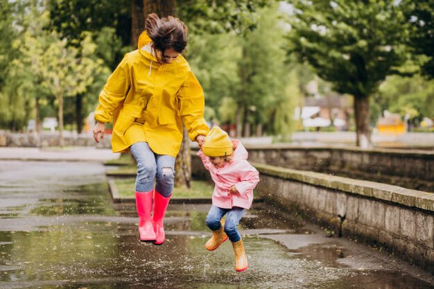 Mother with daughter having fun jumping in puddles Free Photo