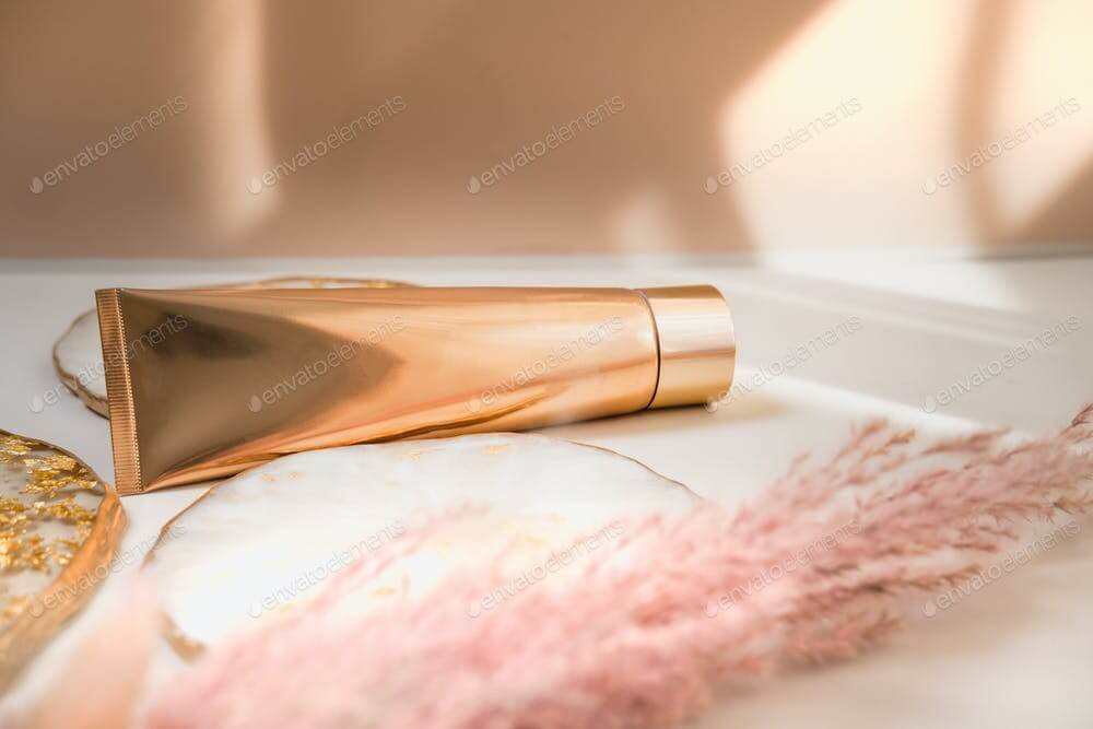 Golden cosmetic tube on pastel color minimalism beauty