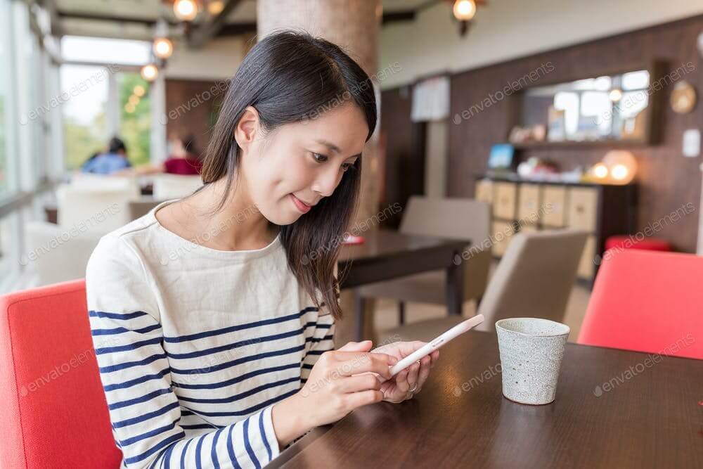 Woman using mobile phone in coffee shop (1)