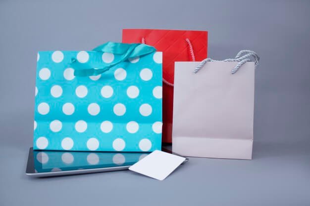 Online shopping concept. close-up tablet mockup with white screen and credit card against the wall of bright gift bags. Premium Photo