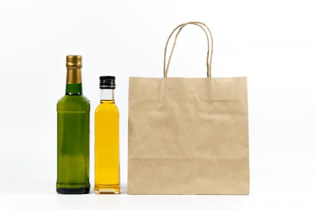 Yellow and green glass bottle with paper bag isolated on a white background. Premium Photo