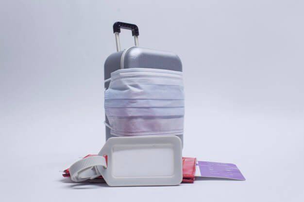 Time to travel. the concept of safe rest during a pandemic covid-19 coronavirus. suitcase for travel with a medical mask and plane tickets with a passport and tag mockup. Premium Photo